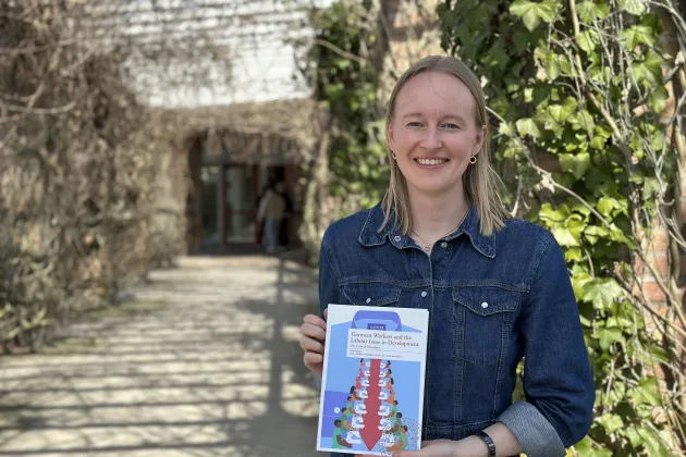 Linn Ternsjö outside a building, with a book in her hands. Photo