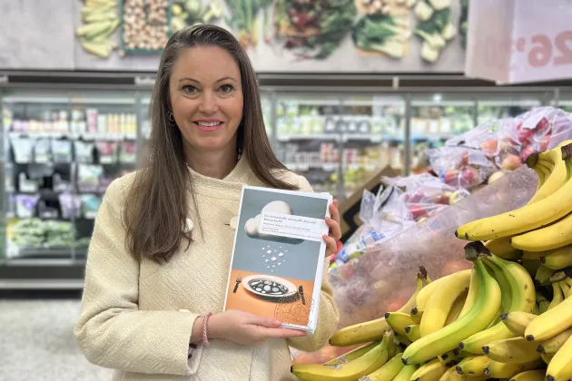 Anna bland bananer i matbutik. Foto